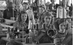 Svartvit bild unga kvinnor vid symaskiner i fabrik